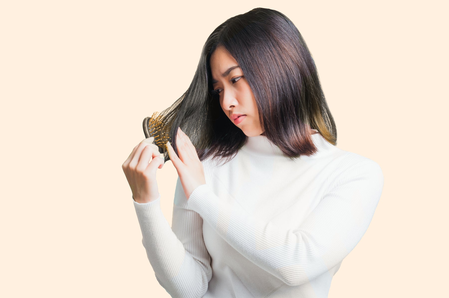 A woman looks at her brush to see if she is losing more hair. Hair loss